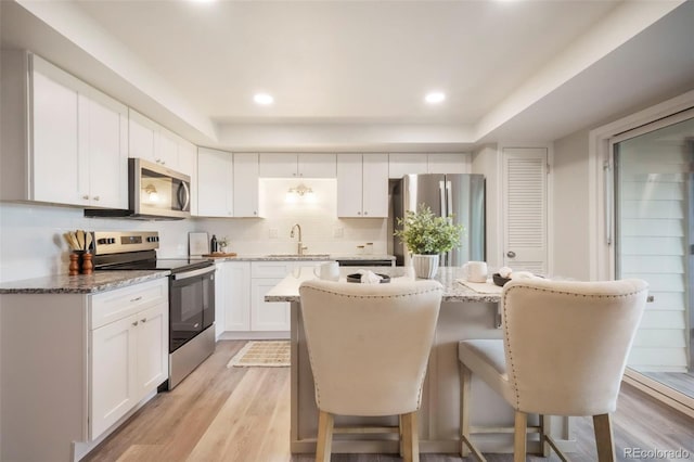 404 Raspberry Ln, Monument, CO 80132 - kitchen featuring stainless steel appliances, a sink, a tray ceiling, a breakfast bar area, and decorative backsplash