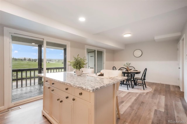 404 Raspberry Ln, Monument, CO 80132 - kitchen featuring a kitchen island, light wood-style flooring, baseboards, and light stone counters