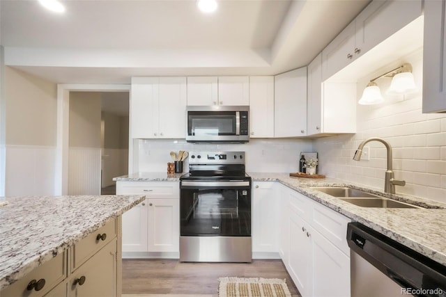 404 Raspberry Ln, Monument, CO 80132 - kitchen with appliances with stainless steel finishes, a sink, backsplash, light stone counters, and wainscoting