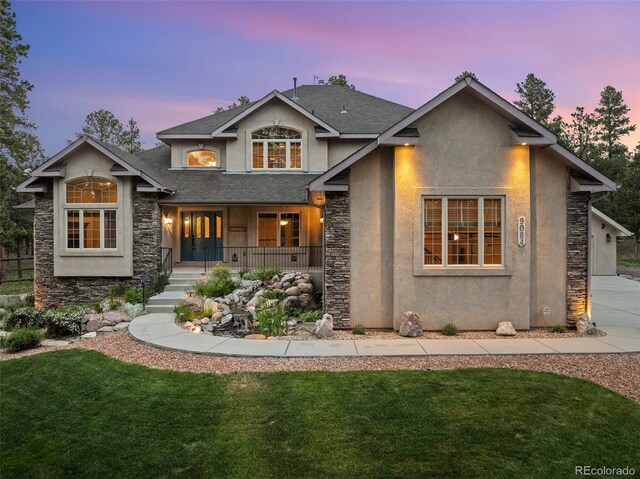 view of front of property featuring a porch, a lawn, and a garage