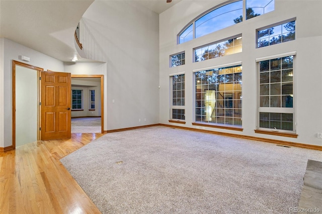 living room with a towering ceiling and light wood-type flooring