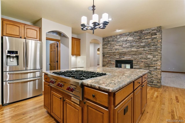 kitchen featuring decorative light fixtures, a chandelier, light hardwood / wood-style flooring, a kitchen island, and appliances with stainless steel finishes