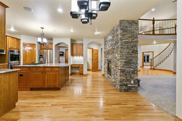 kitchen with light carpet, stainless steel appliances, a fireplace, pendant lighting, and a center island