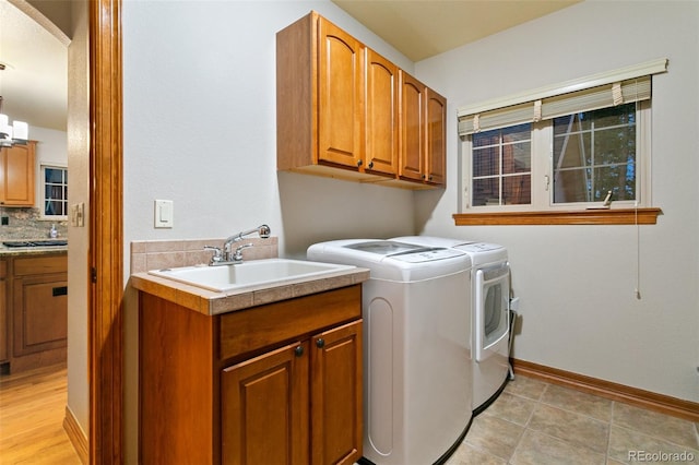 washroom featuring sink, washing machine and clothes dryer, cabinets, and light tile floors