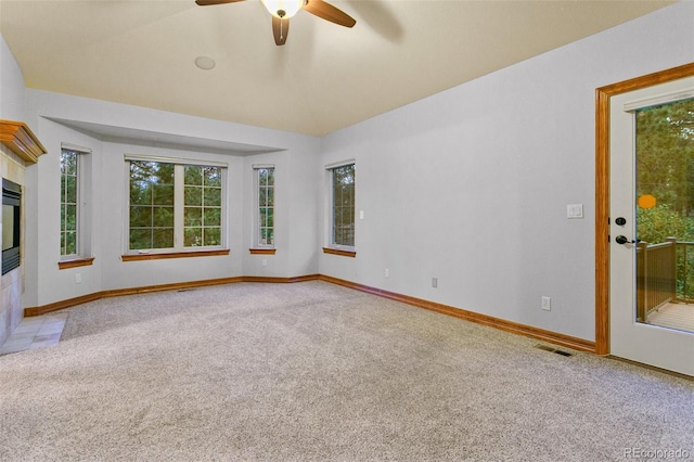 unfurnished living room featuring carpet, ceiling fan, a fireplace, and lofted ceiling