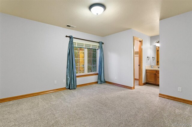 unfurnished bedroom with a walk in closet, a closet, connected bathroom, and light colored carpet