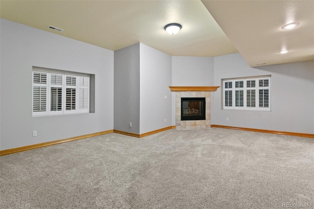 unfurnished living room featuring carpet flooring and a tiled fireplace