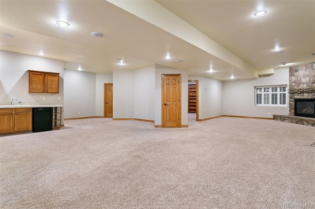 unfurnished living room featuring light colored carpet, sink, and a fireplace