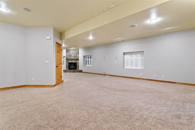 unfurnished living room with a stone fireplace and carpet flooring