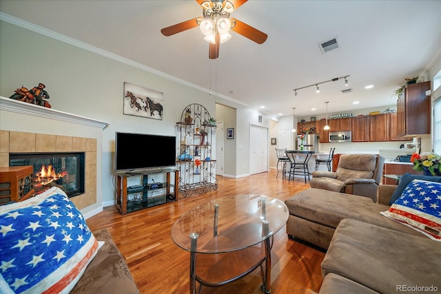 12856 King St, Broomfield, CO 80020 - living area with light wood-type flooring, ceiling fan, ornamental molding, rail lighting, and a fireplace