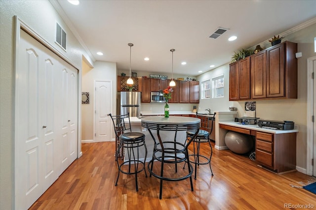 12856 King St, Broomfield, CO 80020 - kitchen with stainless steel appliances, light countertops, light wood-type flooring, a breakfast bar area, and ornamental molding