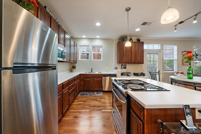 12856 King St, Broomfield, CO 80020 - kitchen featuring appliances with stainless steel finishes, light wood finished floors, light countertops, decorative light fixtures, and a kitchen island