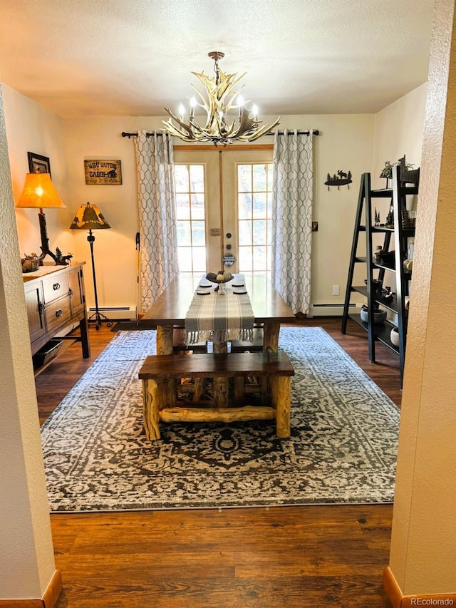 dining room featuring hardwood / wood-style flooring, baseboard heating, french doors, and a notable chandelier