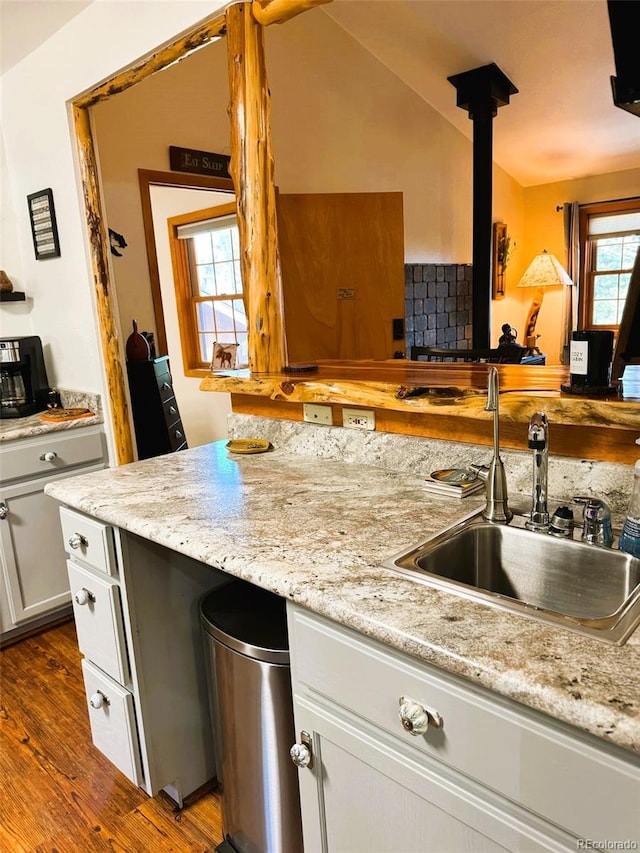 kitchen with sink, white cabinetry, hardwood / wood-style flooring, and light stone countertops