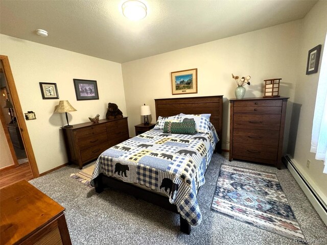 bedroom featuring light carpet, baseboard heating, and baseboards