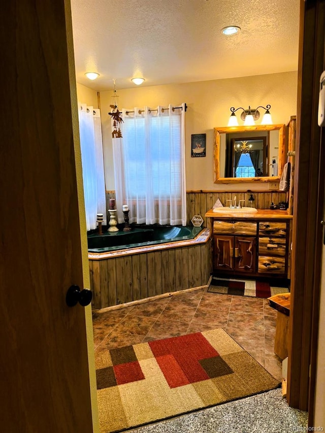 bathroom with a tub, vanity, tile patterned floors, and a textured ceiling