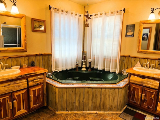 full bathroom with two vanities, a wainscoted wall, a sink, and a bath