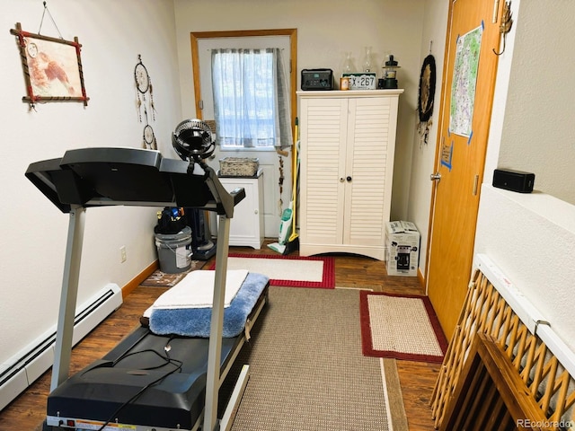 workout room featuring dark wood-type flooring and a baseboard heating unit