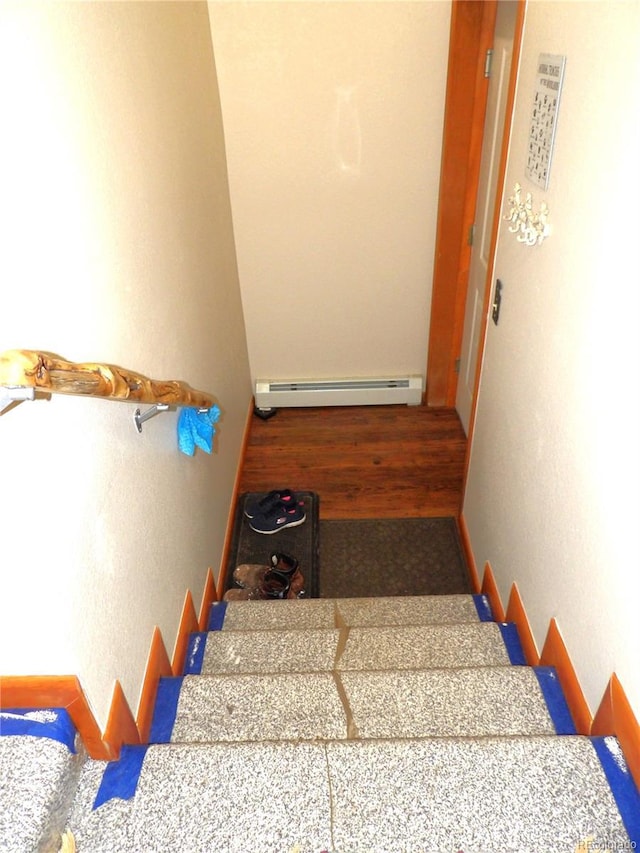 staircase featuring baseboards and a baseboard heating unit