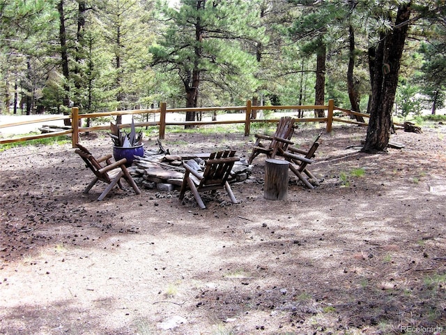 exterior space featuring an outdoor fire pit and a wooded view