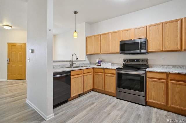 kitchen featuring baseboards, appliances with stainless steel finishes, light wood-type flooring, pendant lighting, and a sink