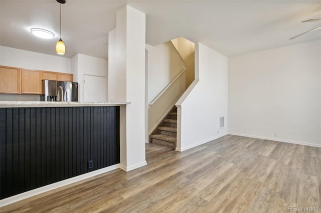 interior space with light countertops, light wood-type flooring, stainless steel fridge, and decorative light fixtures