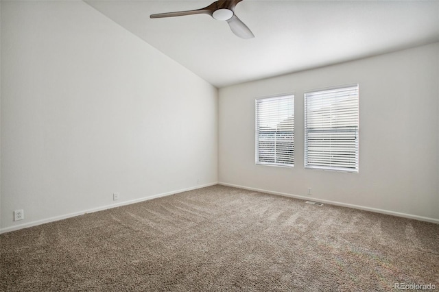 carpeted spare room featuring a ceiling fan, vaulted ceiling, and baseboards