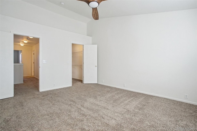 unfurnished bedroom featuring a walk in closet, a closet, ceiling fan, and carpet