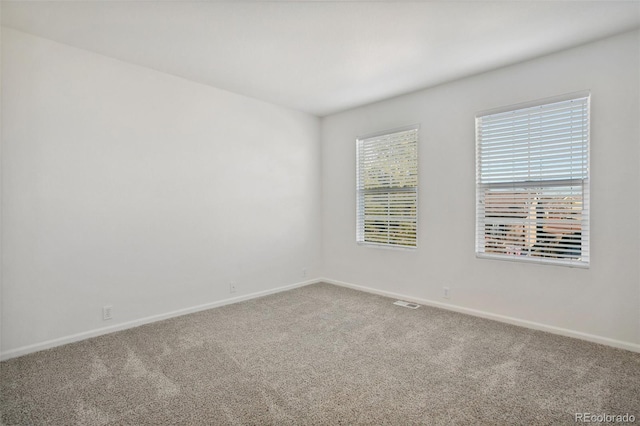 spare room featuring carpet floors and baseboards