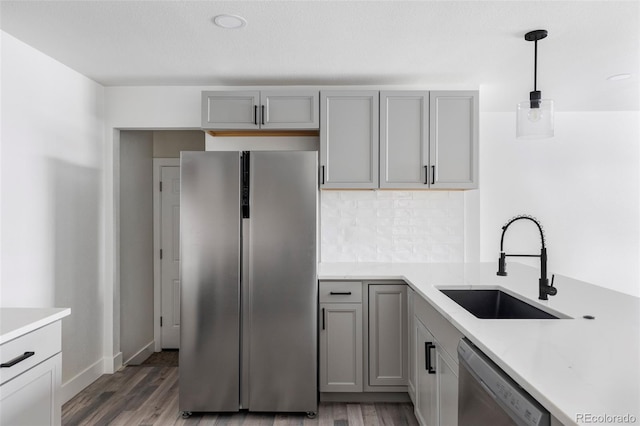 kitchen featuring pendant lighting, sink, gray cabinets, and stainless steel appliances