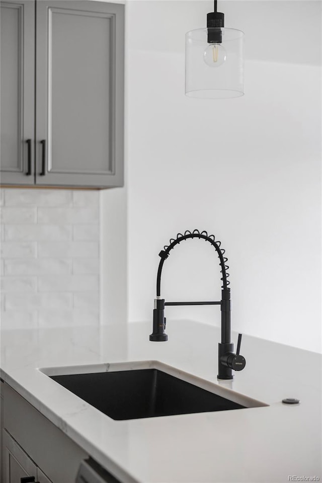 interior details featuring light stone countertops, gray cabinets, sink, and hanging light fixtures