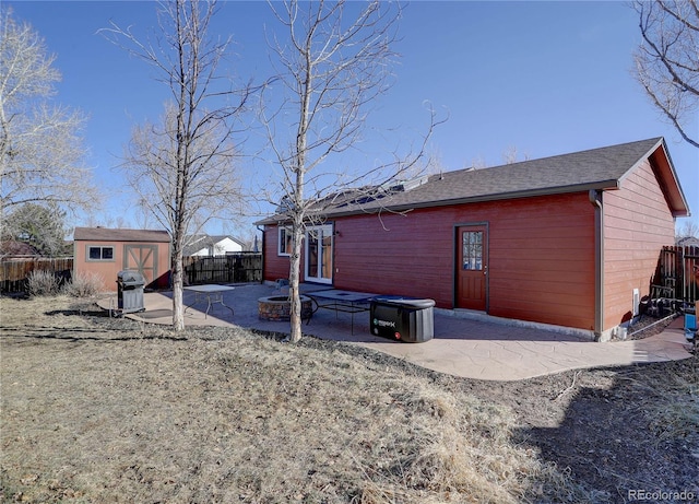 back of property with a fire pit, a storage unit, and a patio area