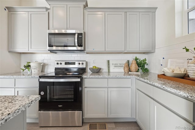 kitchen with stainless steel appliances, backsplash, and light stone counters