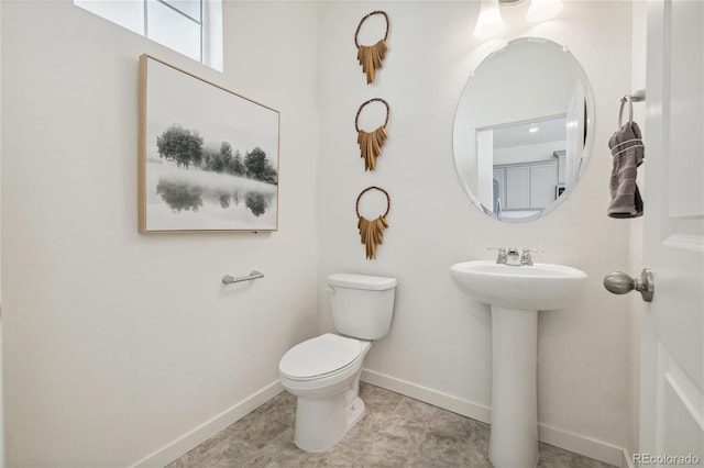half bath featuring baseboards and toilet