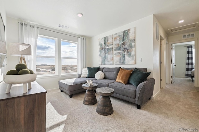 living area with attic access, light colored carpet, baseboards, and visible vents