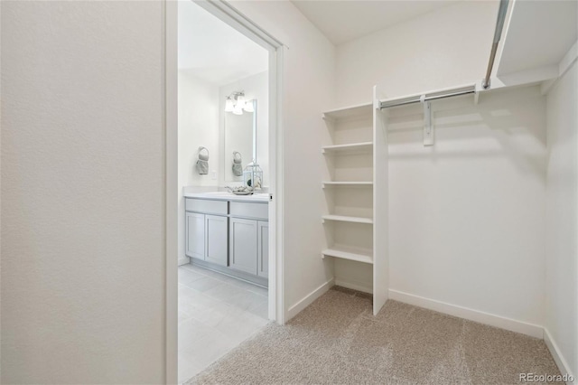 walk in closet with light carpet and a sink