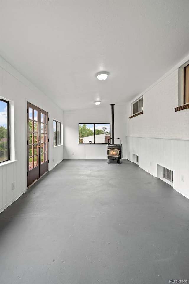 6627 Eaton St, Arvada, CO 80003 - unfurnished living room featuring finished concrete floors, a wood stove, french doors, and a decorative wall