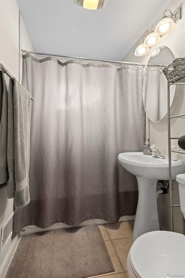 6627 Eaton St, Arvada, CO 80003 - full bath featuring toilet, tile patterned flooring, curtained shower, and a textured ceiling