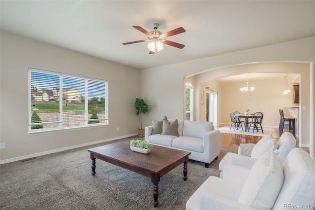 carpeted living room featuring ceiling fan with notable chandelier