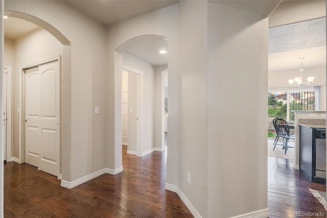 corridor with a notable chandelier and dark wood-type flooring