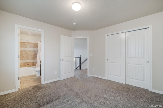 unfurnished bedroom with a closet, carpet floors, and ensuite bath