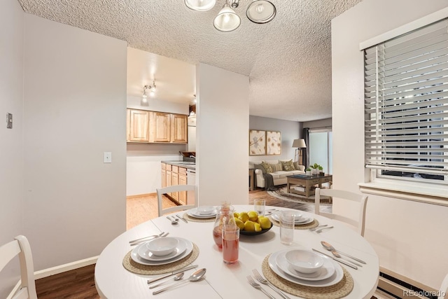 dining space featuring wood-type flooring and a textured ceiling