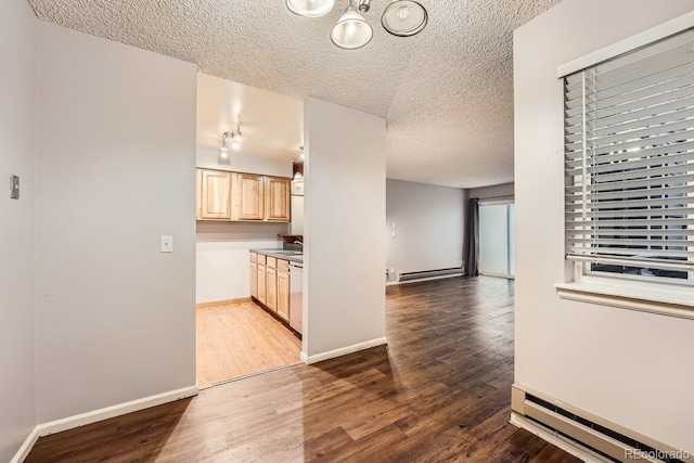 kitchen with wood-type flooring, light brown cabinets, a textured ceiling, and a baseboard radiator