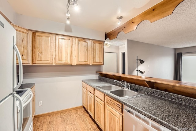 kitchen featuring white appliances, a textured ceiling, light hardwood / wood-style floors, sink, and light brown cabinetry