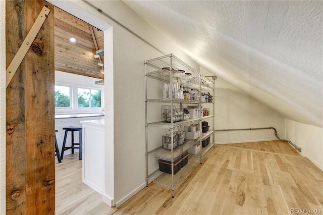 additional living space with lofted ceiling, a textured ceiling, and wood finished floors