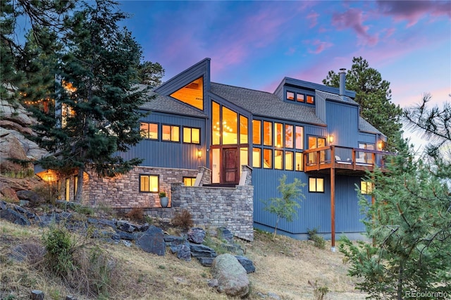 back of property with a shingled roof and a chimney