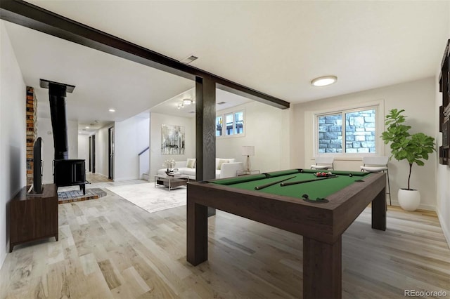 rec room with a wealth of natural light, light wood finished floors, and a wood stove