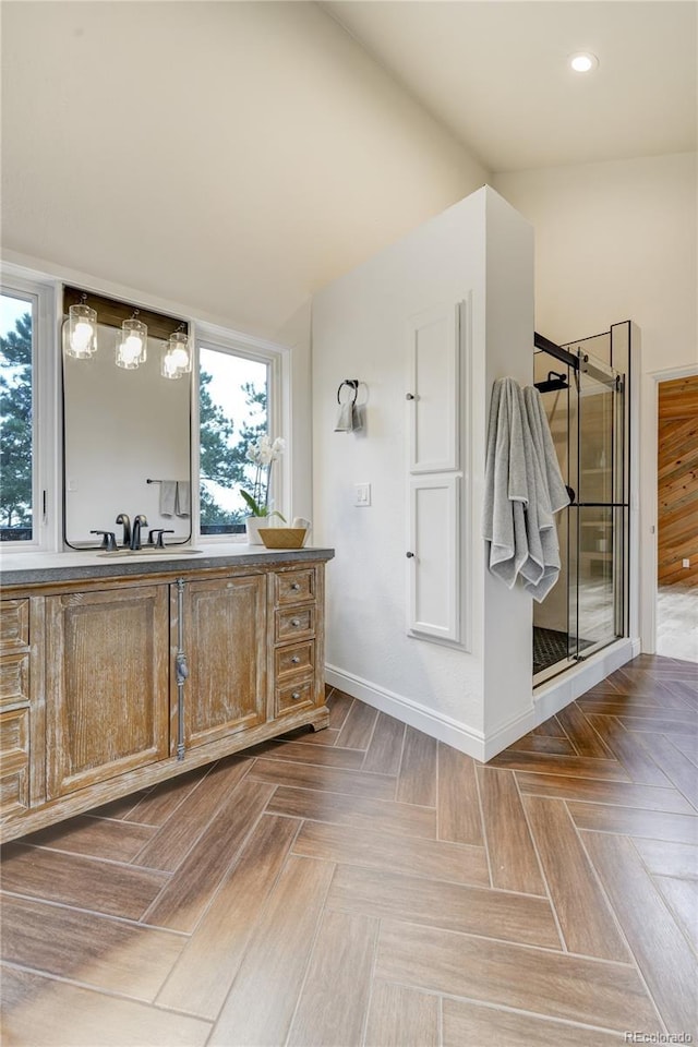 bathroom with a shower with door, vanity, a wealth of natural light, and baseboards