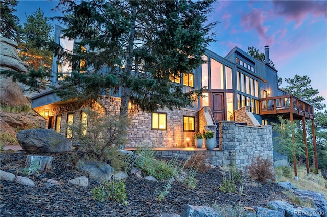 property exterior at dusk featuring stone siding