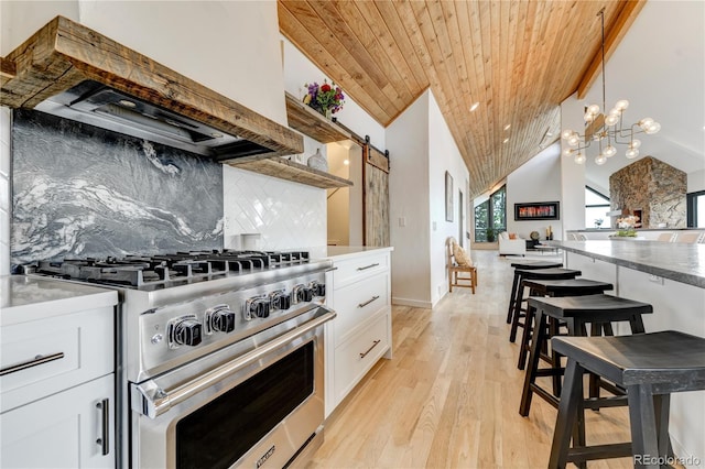 kitchen with a barn door, decorative backsplash, wood ceiling, custom range hood, and high end range